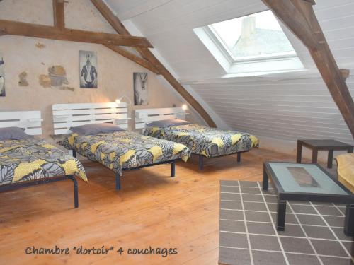 Cette chambre mansardée comprend 3 lits et une fenêtre. dans l'établissement Grande maison familiale avec jardin, terrasse et équipements de loisirs, proche forêt de la Charnie - FR-1-410-297, à Chemiré-en-Charnie