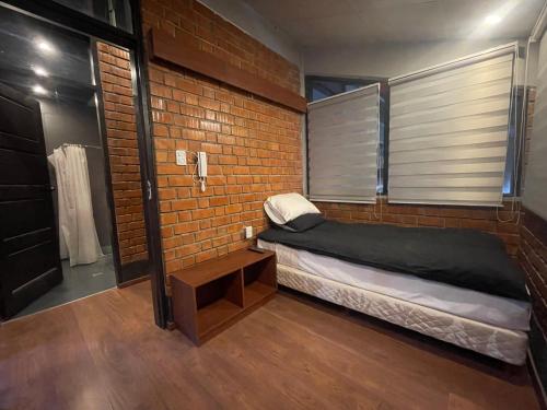 a bedroom with a bed and a brick wall at Onkel Inn Wagon Sleepbox Uyuni in Uyuni
