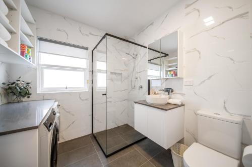 a white bathroom with a shower and a sink at The Tea House - Apartment 1 in Keswick