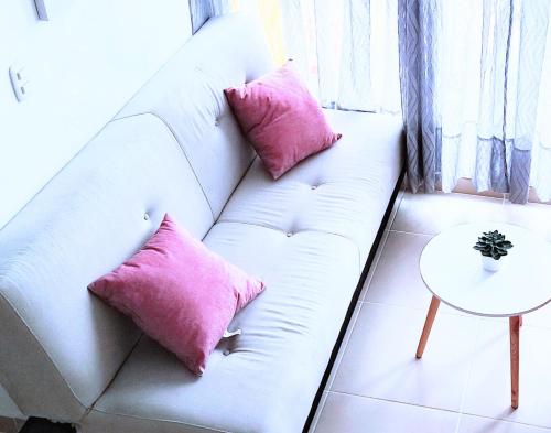a white couch with pink pillows in a living room at Acogedor Apartamento en Armenia, totalmente amoblado. in Armenia