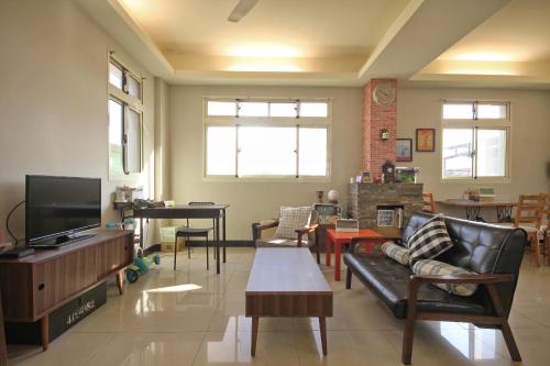 a living room with a couch and a tv at Happy Tree Hostel in Jinning