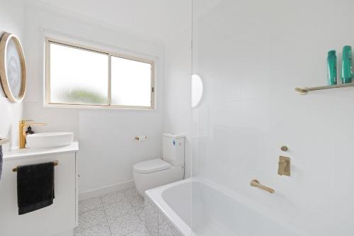 a white bathroom with a tub and a sink at Lazy Daze at SummerHaze in Cape Woolamai