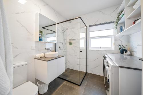 a white bathroom with a shower and a toilet at Two Tea House - Contemporary Courtyard Comfort in Keswick