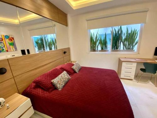 - une chambre avec un lit rouge, un bureau et deux fenêtres dans l'établissement Cozy and Deluxe Apartment at the Heart of Ipanema, à Rio de Janeiro