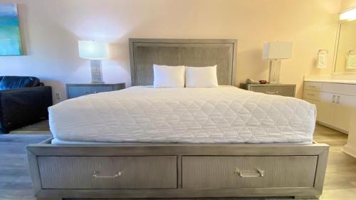 um quarto com uma cama grande e lençóis brancos em Royal Inn Hotel em Royal Palm Beach