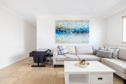 a living room with a white couch and a piano at Sunrise Serenity in Salamander Bay
