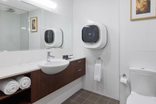 a bathroom with a sink and a toilet and a tv at Amora Hotel Riverwalk Melbourne in Melbourne