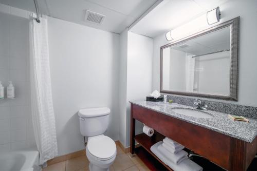 a bathroom with a sink and a toilet and a mirror at Country Inn & Suites by Radisson, Ontario at Ontario Mills, CA in Ontario