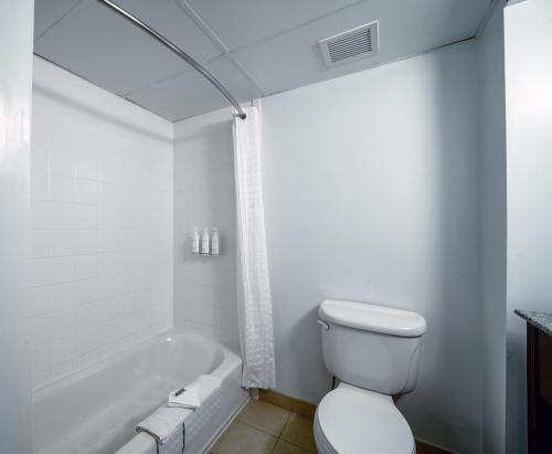 a white bathroom with a toilet and a bath tub at Country Inn & Suites by Radisson, Ontario at Ontario Mills, CA in Ontario