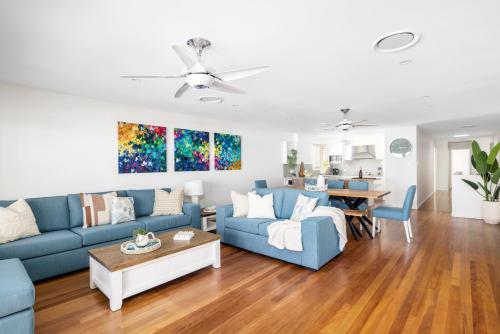 a living room with blue couches and a table at Sunrise Serenity in Salamander Bay