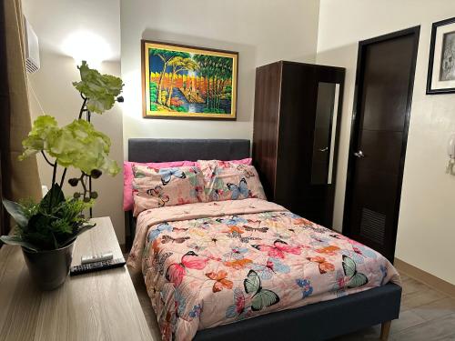 a bedroom with a bed with a comforter and a table at One Regis Bacolod- Upper East Studio Room in Bacolod