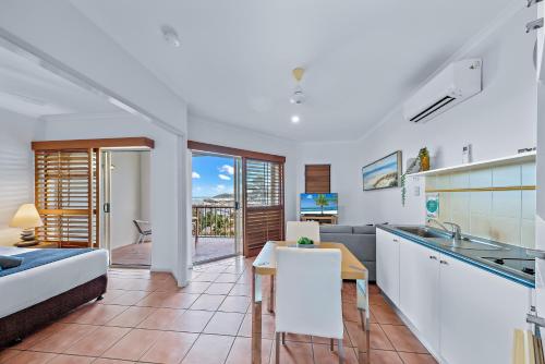 a kitchen and living room with a bed and a table at Spa Haven 17B Ocean View in Airlie Beach