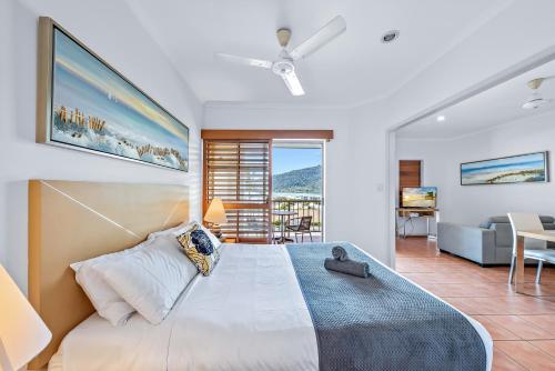 a bedroom with a large bed and a living room at Spa Haven 17B Ocean View in Airlie Beach