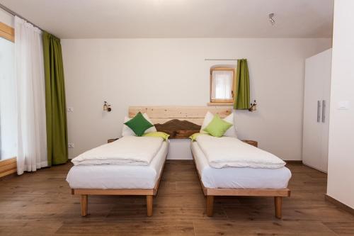 duas camas num quarto com cortinas verdes em B&B Incanto em Cles