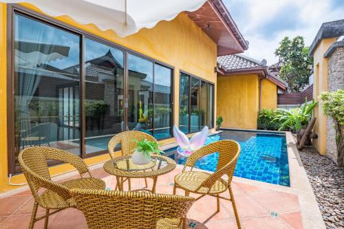 a patio with chairs and a table and a pool at Asia Paradise Pool Villa, Jomtien Beach, Pattaya in Jomtien Beach
