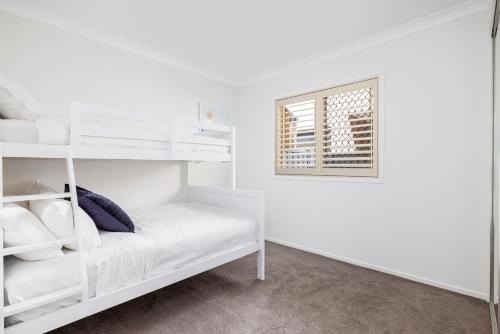 a white bedroom with a bunk bed and a window at Sunrise Serenity in Salamander Bay