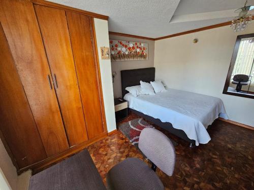 a bedroom with a bed and a cabinet and two chairs at Aparta estudio de la panamericana in Pasto