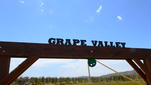 a sign for grape valley with a view of a field at Grape Valley Old West Cabins in Ensenada