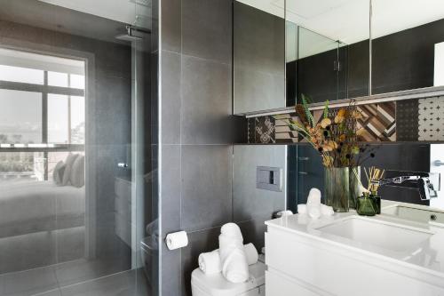 een badkamer met een toilet, een wastafel en een spiegel bij Modern Elegance Caulfield North in Melbourne