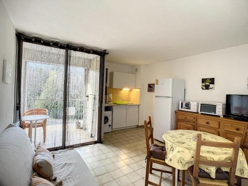 une petite cuisine avec une table et un réfrigérateur dans l'établissement Appartement F2 avec Terrasse, Wifi et Proximité Thermes à Lamalou-les-Bains - FR-1-451-118, à Lamalou-les-Bains