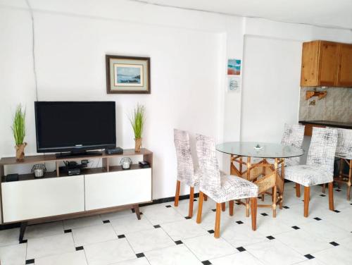 - un salon avec une télévision, une table et des chaises dans l'établissement Acogedor Departamento en la Playa, à Punta Hermosa