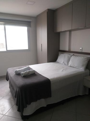 1 dormitorio con 1 cama grande con sábanas blancas y ventana en Flat Centro de São Paulo, en São Paulo
