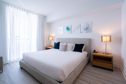 a bedroom with a large white bed and a window at Luxury Oceanview Apartment in Hallandale Beach