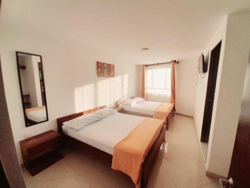 a hotel room with two beds and a mirror at HOTEL LA RUEDA SR in Barbosa