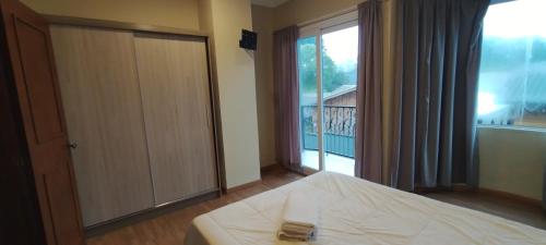 a bedroom with a bed and a large window at Casa Joaninha centro in Canela
