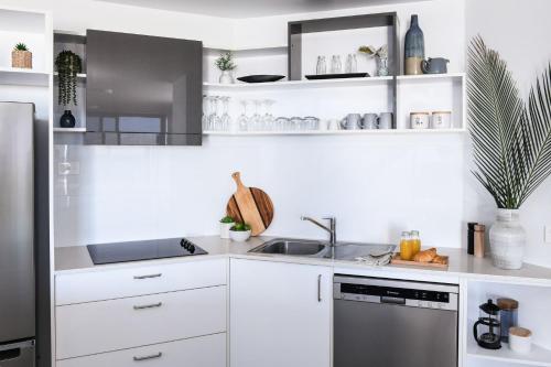 a kitchen with white cabinets and a sink at Pacific Dawn on the Beach One in Wooli