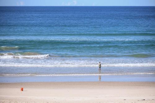 a person standing on the beach looking at the ocean at Pacific Dawn on the Beach One in Wooli