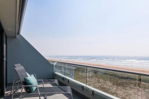 a balcony with a chair and a view of the beach at Pacific Dawn on the Beach One in Wooli