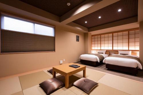 two beds in a room with a table and chairs at Rinn Kitagomon in Kyoto