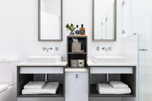La salle de bains est pourvue de 2 lavabos et de 2 miroirs. dans l'établissement Pacific Dawn on the Beach, à Wooli