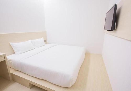 a bedroom with a white bed and a tv on a wall at Minimalist Hotel in Johor Bahru