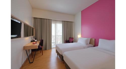um quarto de hotel com duas camas e uma televisão em Quest Hotel Simpang Lima - Semarang by ASTON em Semarang