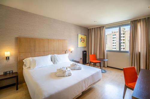 ein Hotelzimmer mit einem großen weißen Bett mit orangefarbenen Stühlen in der Unterkunft Abba Huesca in Huesca