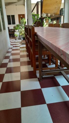een houten tafel en stoelen op een geruite vloer bij Hotel rejeki in Lewoleba