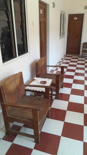 Habitación con sillas de madera y suelo a cuadros. en Hotel rejeki, en Lewoleba