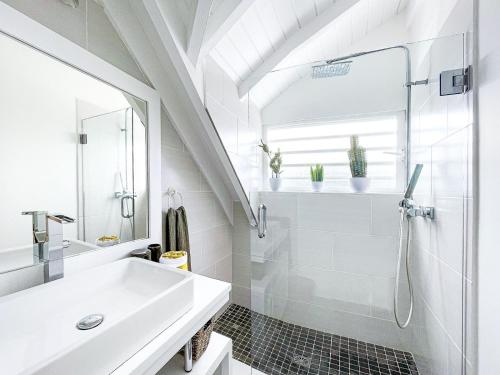 La salle de bains blanche est pourvue d'un lavabo et d'une douche. dans l'établissement Studio CASA SUN, à Saint-Martin