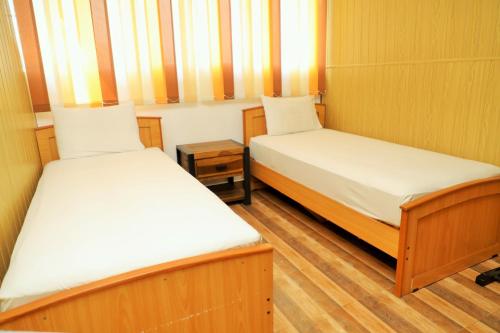 two beds in a small room with wooden floors at Andorra Tourist Resort Anuradhapura in Anuradhapura