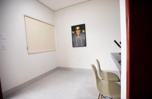 um quarto branco com uma cadeira e uma fotografia na parede em Capuzzo Flat 2 em Redenção