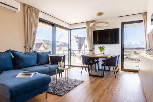 a living room with a blue couch and a table at Góralski Resort Family & SPA in Białka Tatrzanska