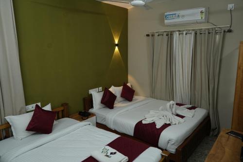 two beds in a hotel room with towels on them at Dreams Paradise Airport Residency in Nedumbassery