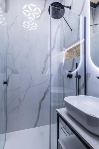 a white bathroom with a shower and a sink at Góralski Resort Family & SPA in Białka Tatrzanska