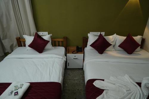 a hotel room with two beds with red and white pillows at Dreams Paradise Airport Residency in Nedumbassery