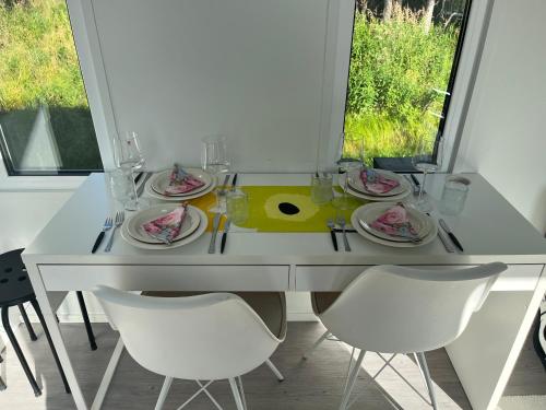 a white dining table with white chairs and plates of food at Luxus Tiny House Saagala in Tornio
