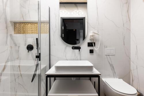 a white bathroom with a sink and a shower at Góralski Resort Family & SPA in Białka Tatrzanska