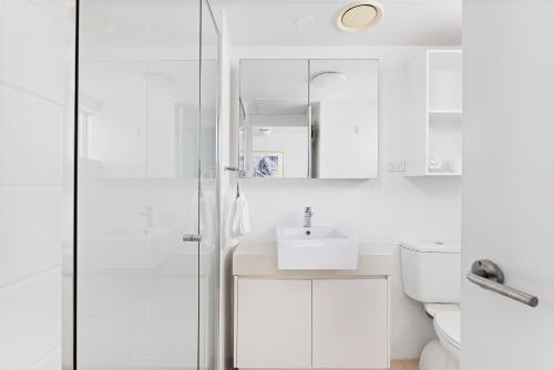 a white bathroom with a shower and a sink at Cote D'Azur Resort in Nelson Bay