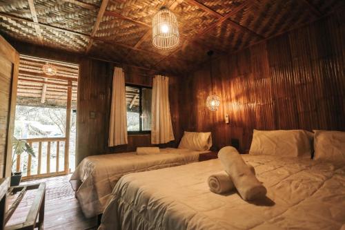 1 dormitorio con 2 camas en una habitación con paredes de madera en Marika Resort, en Badian